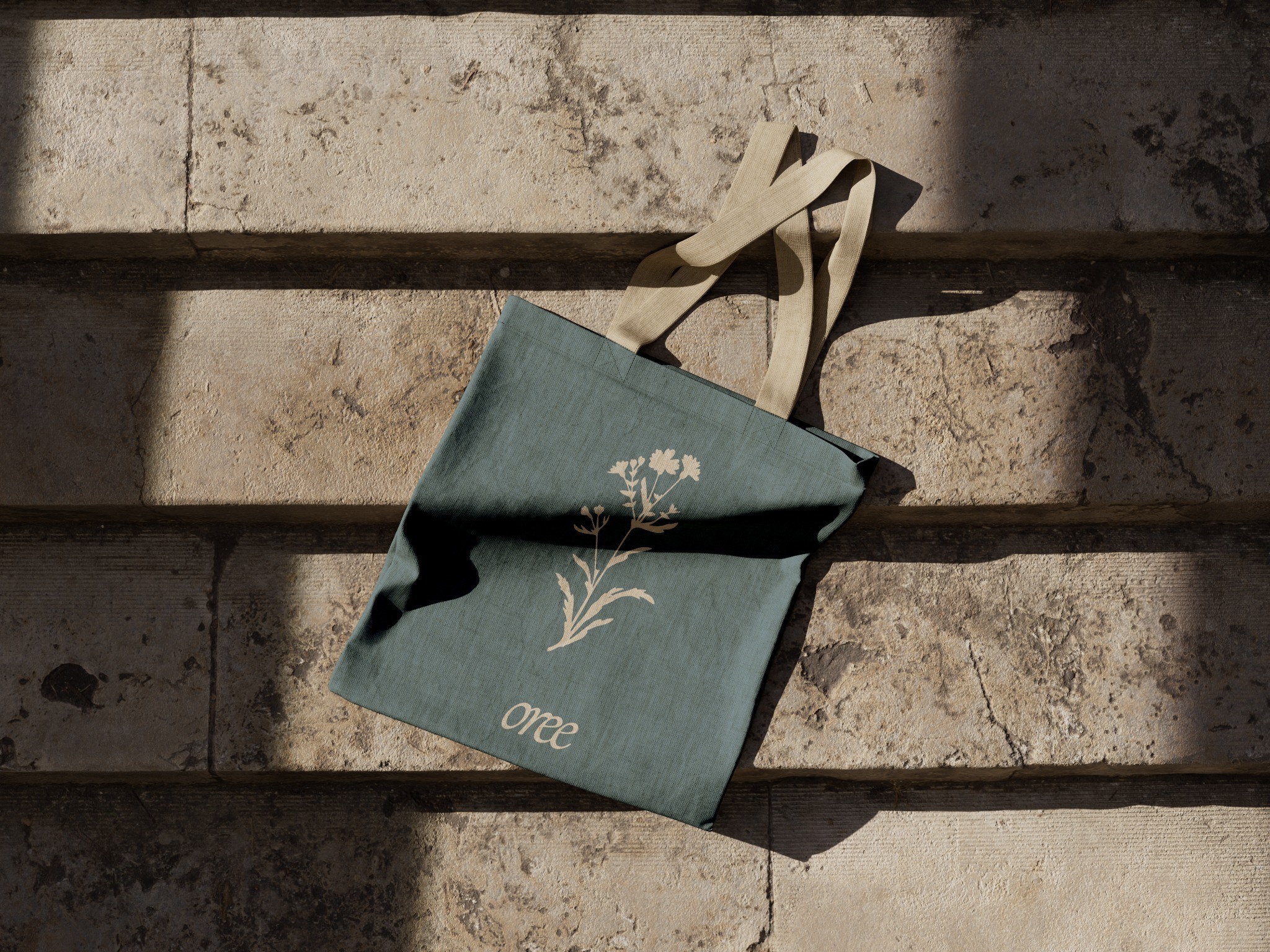 Blue-grey tote bag with a pale botanical motif in sunlight
