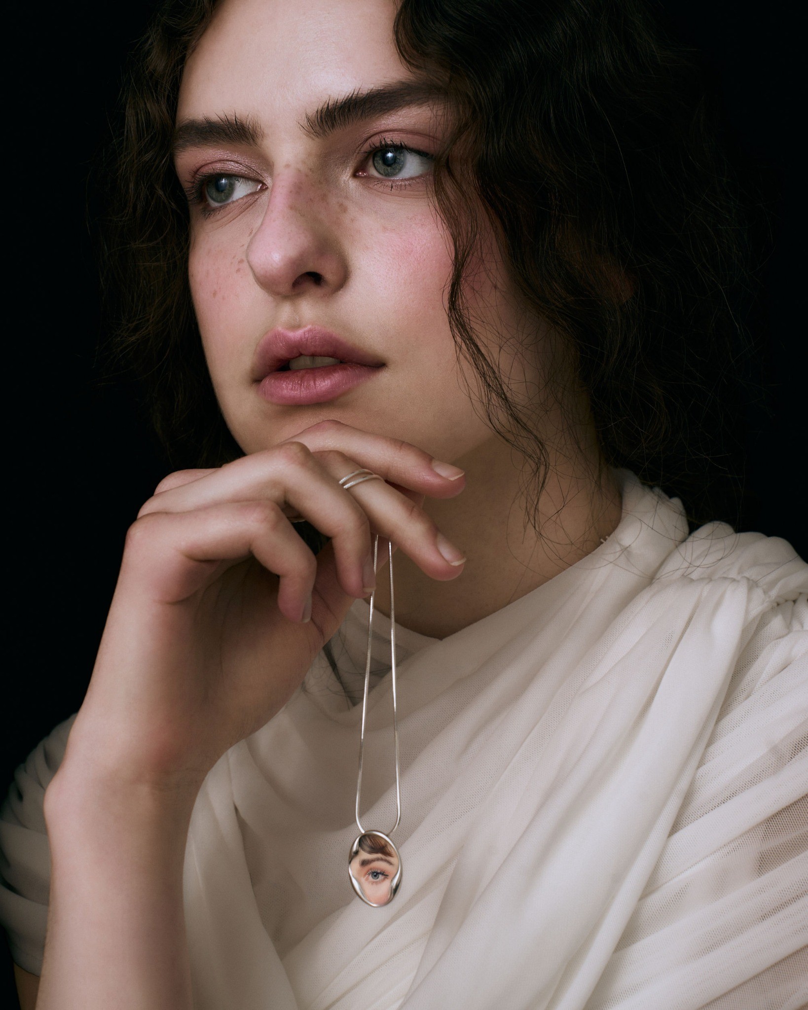 Pendant held on its chain with an eye portrait ring on the hand